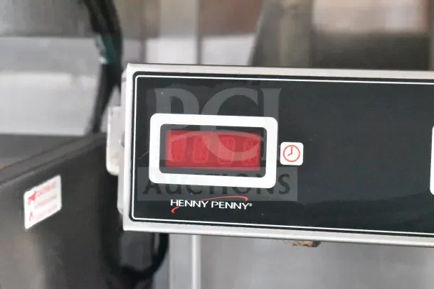 Henny Penny equipment display with digital readout, showing time settings. Visible label for fire suppression system warning.