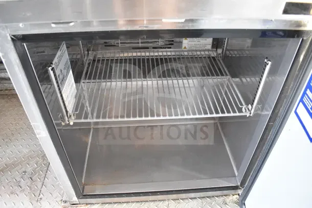 Interior view of a refrigeration unit inside the 2021 Rock Solid Cargo 8.5'x28' food trailer, featuring wire shelving.