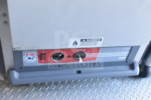 Control panel of a Metro C5 holding cabinet inside a 2021 Rock Solid Cargo food trailer, featuring a temperature dial and warning label.