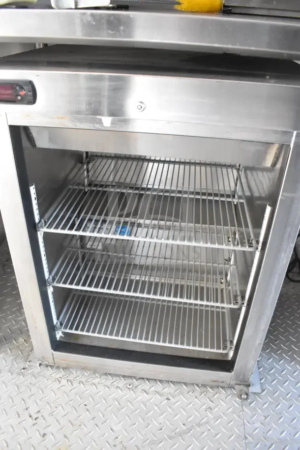 Stainless steel refrigerator interior with three wire shelves, part of the 2021 Rock Solid Cargo food trailer.
