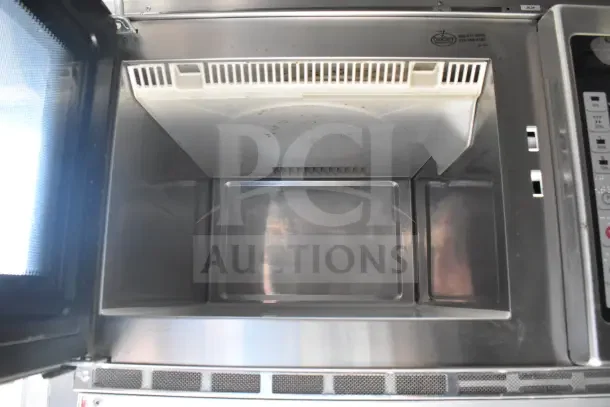 Interior view of a stainless steel appliance within a 2021 Rock Solid Cargo 8.5'x28' food trailer, featuring a Camsave door.