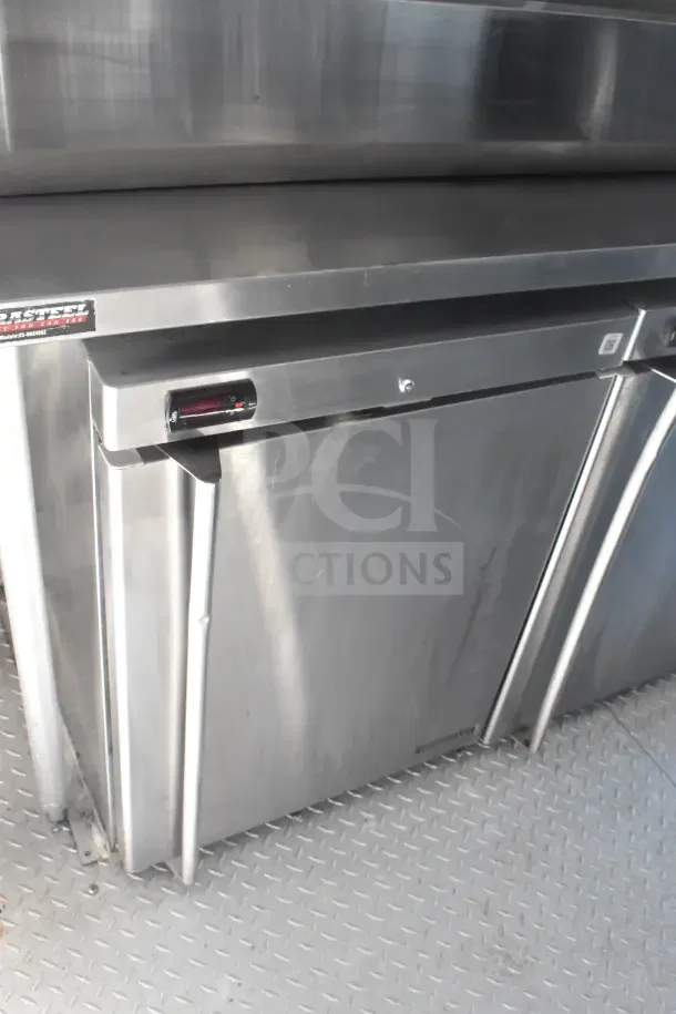 2021 Rock Solid Cargo 8.5'x28' food trailer interior. Features refrigeration unit, stainless surface, visible CaptiveAire hood tag.