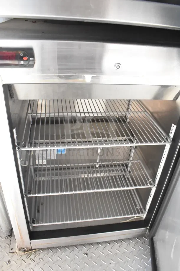 Stainless steel commercial refrigerator interior with wire shelves, temperature control panel, and clean condition.