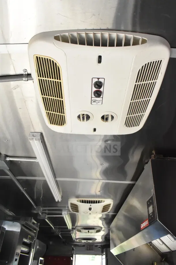 2021 Rock Solid Cargo food trailer interior with CaptiveAire hood, air vents, and fluorescent lighting, showcasing commercial kitchen setup.