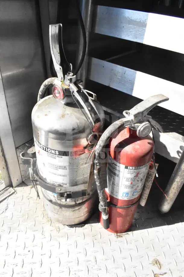 2021 Rock Solid Cargo food trailer fire extinguishers with visible instructions and safety pins, part of fire suppression system.