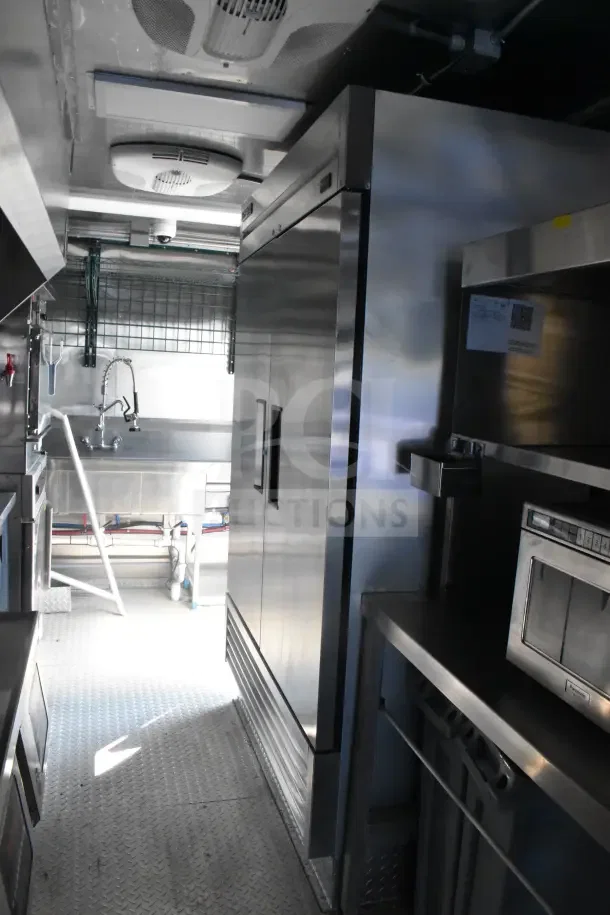 2021 Texino 8.5'x28' food trailer interior with CaptiveAire grease hood, fire suppression system, refrigeration, and breading tables.