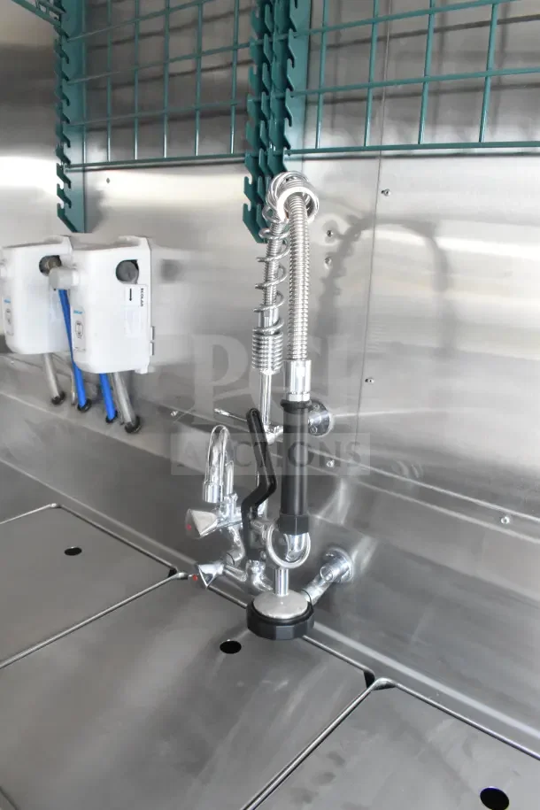Stainless steel interior sink with industrial faucet in 2021 Texino food trailer. Features visible piping and storage racks.
