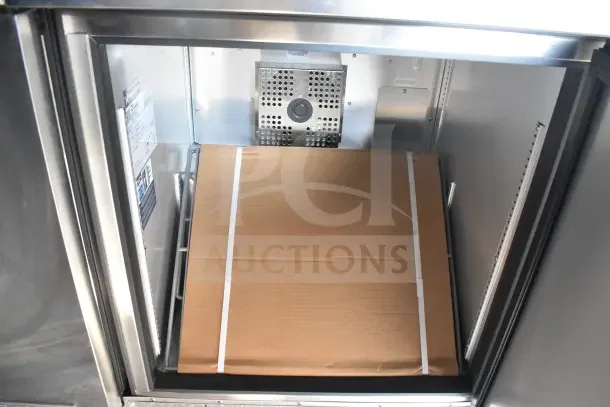 Interior of 2021 Texino food trailer refrigeration unit, showing a packaged item on shelving within a stainless steel compartment.