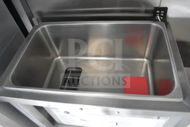 Stainless steel sink in Texino food trailer with integrated drainage and red cleaning pad.