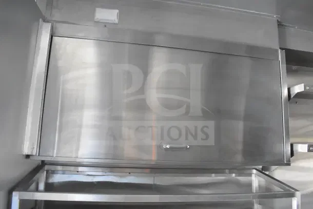 2021 Texino food trailer interior with CaptiveAire grease hood, stainless steel finish, refrigeration unit below.