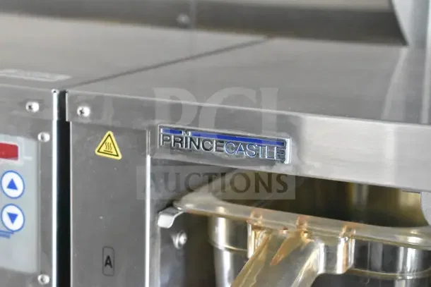 Prince Castle kitchen appliance in stainless steel with visible control buttons and caution symbols.