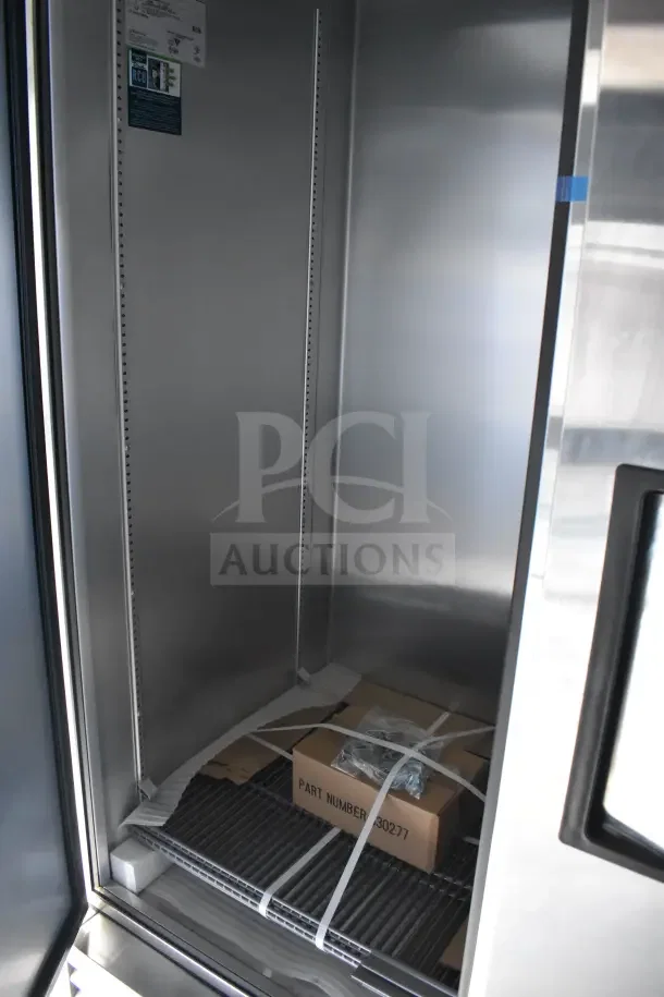 Interior of 2021 Texino food trailer with stainless steel refrigeration unit, shelving, and boxed equipment on the floor.