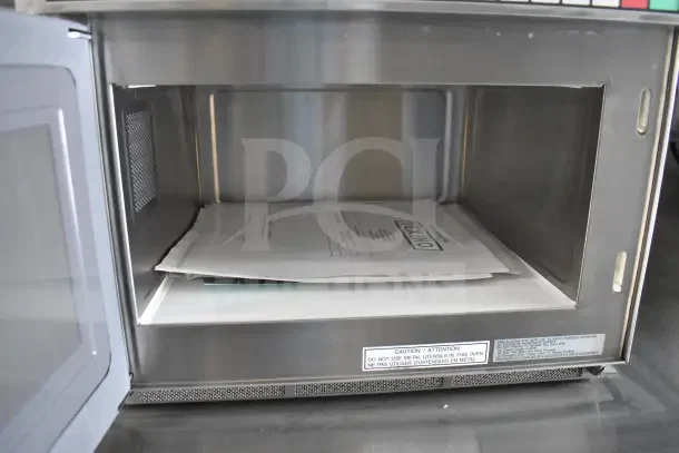 Interior view of a Texino food trailer showing a microwave with Texino documents inside. Visible caution label on front.