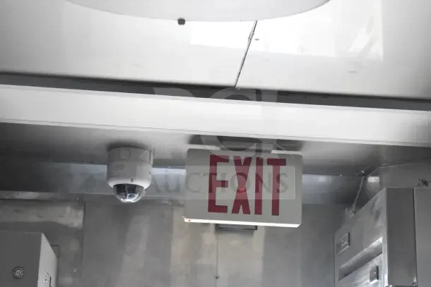 Ceiling view of Texino food trailer interior with a surveillance camera and illuminated EXIT sign.