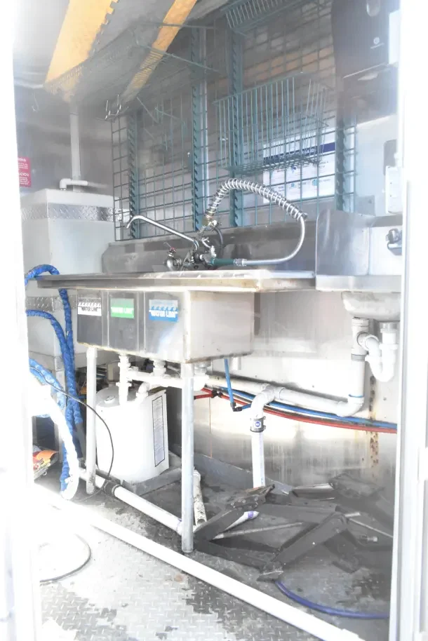 2020 Diamond Cargo 24' kitchen trailer interior with sink and plumbing. Features grease hood, Pitco fryer, Wells griddle, Arctic Air suite.