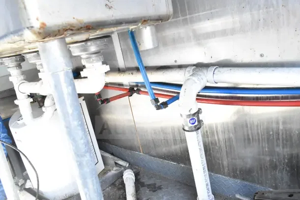 Under-sink plumbing of 2020 Diamond Cargo 24' Commercial Kitchen Trailer, featuring labeled piping and NSF-certified connectors.