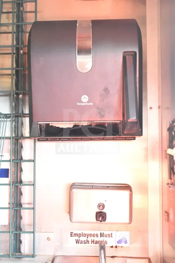 Georgia-Pacific paper towel dispenser and soap dispenser in a commercial kitchen trailer. Sign reads "Employees Must Wash Hands."