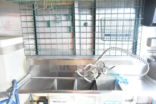 2020 Diamond Cargo 24' kitchen trailer sink area with metal grate storage and handwash sign.
