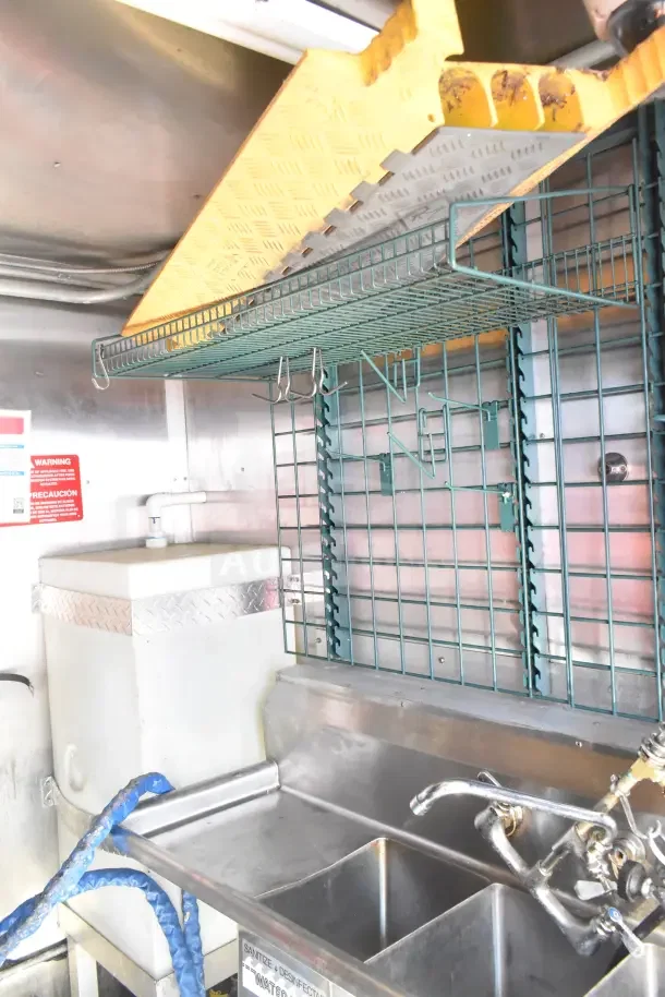 2020 Diamond Cargo 24' kitchen trailer interior featuring wire shelving, stainless sink, and diamond plate detail.