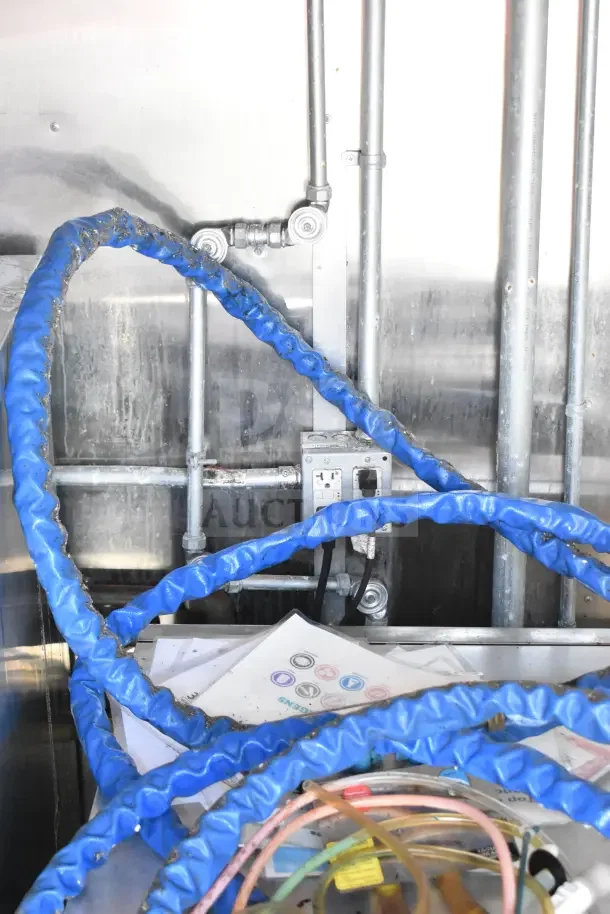 Interior view of a 2020 Diamond Cargo kitchen trailer, showing plumbing and wiring with visible blue hoses and electrical outlets.