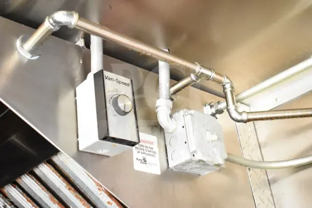 Industrial kitchen ventilation system with a Vari-Speed control unit and caution label in a Diamond Cargo kitchen trailer.