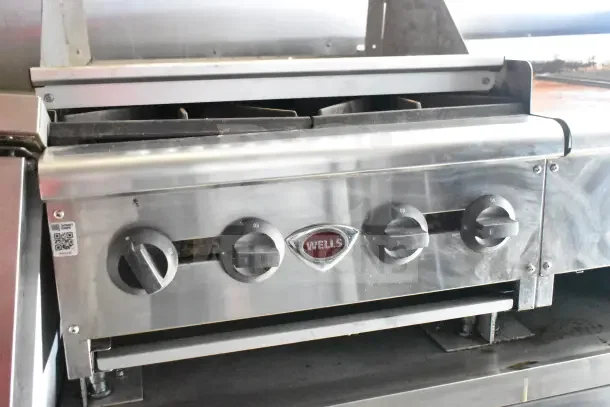 Wells dual griddle in Diamond Cargo kitchen trailer, stainless steel, visible control knobs, includes QR code label.