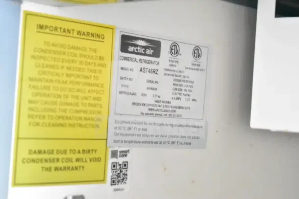 Label from an Arctic Air commercial refrigerator, model AST48RZ, detailing specifications and maintenance warnings.