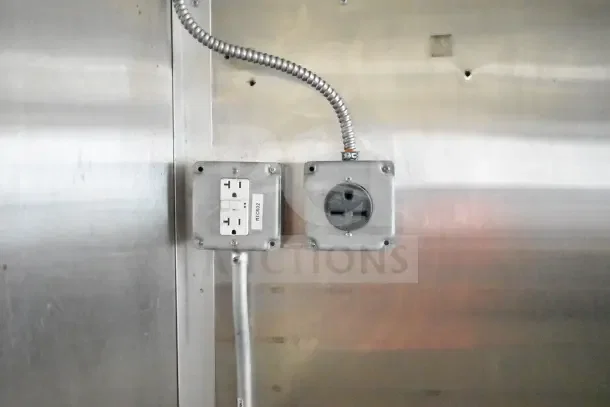 Dual electrical outlets on a stainless steel wall within a 2020 Diamond Cargo commercial kitchen trailer.