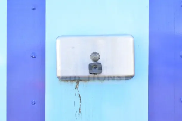 Close-up view of a stainless steel light fixture on a blue metal surface.