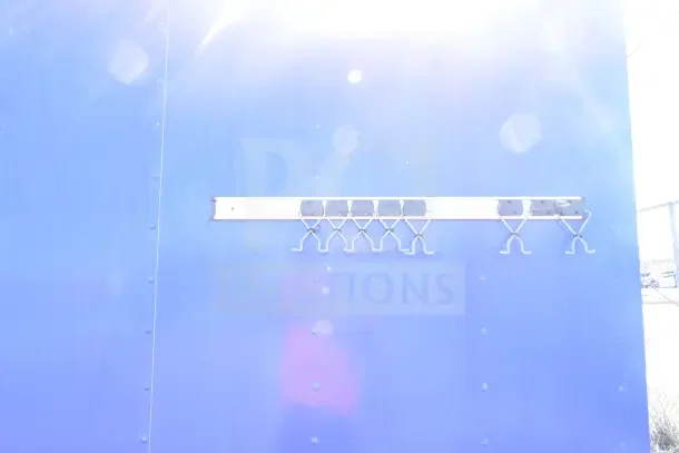 Blue exterior of a 2020 Diamond Cargo 24' kitchen trailer with metal hooks mounted.