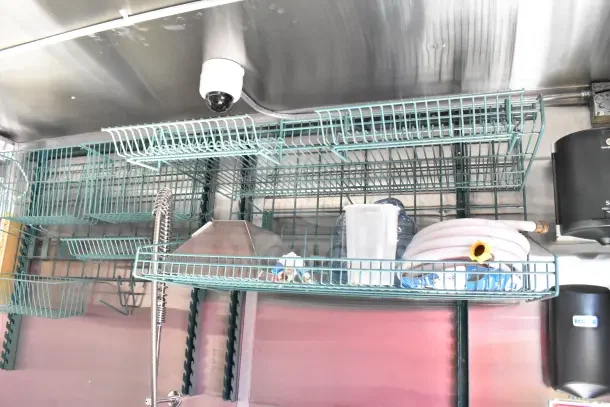 Interior of 2022 Rock Solid Cargo Ghost Kitchen Trailer with shelving, hose, and containers visible. Eco-friendly storage setup.