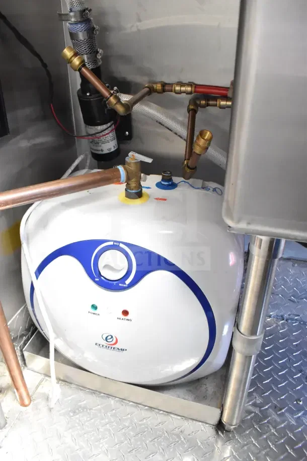 Inside view of 2022 Rock Solid Cargo Ghost Kitchen Trailer showing Eccotemp water heater, copper piping, and fittings.
