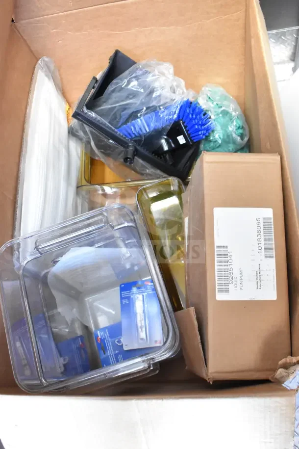 Cardboard box containing kitchen accessories, packaging material, and a labelled liquid fun pump product box.