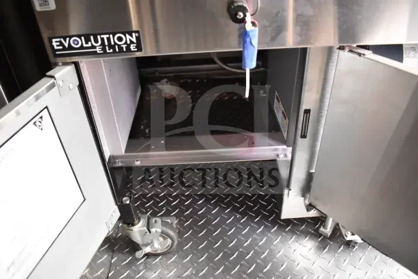 Rock Solid Cargo trailer interior with Evolution Elite signage, showcasing heavy-duty metal flooring and caster wheels.