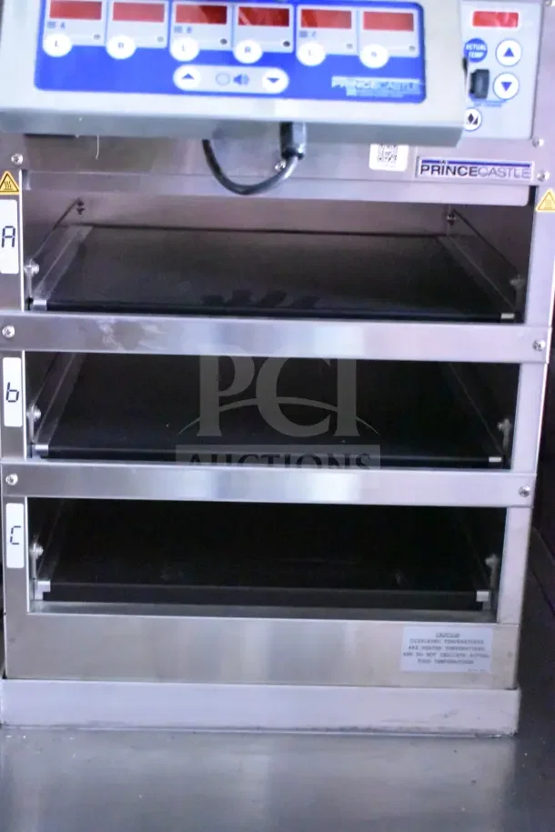 Prince Castle heating cabinet with three shelves, featuring labeled controls and digital display, stainless steel finish.