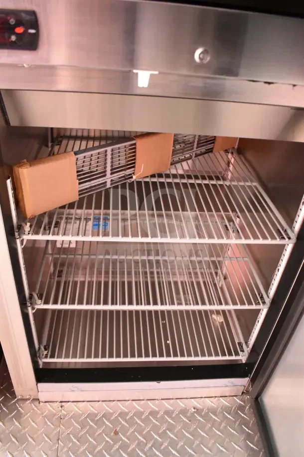 Inside view of Rock Solid Cargo trailer's refrigeration unit, showing empty wire shelves. New condition, VIN: 7H2BE2831ND043576.