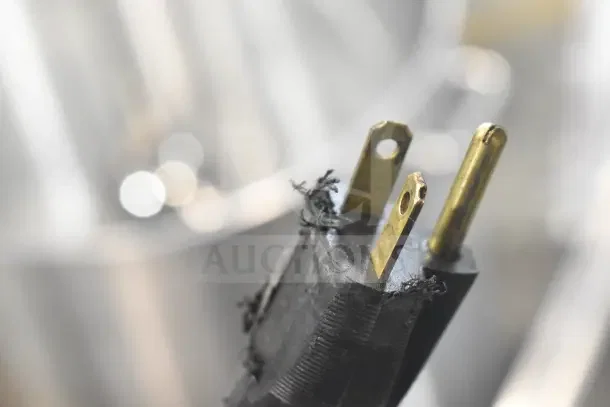 Close-up of a frayed electrical plug with brass prongs for a Stoelting F131-38I2 ice cream machine, 208-240V, 1 phase.