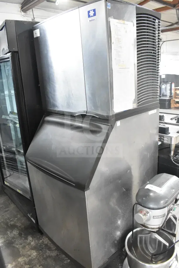 Manitowoc SY0874C commercial ice machine head on ice bin, stainless steel, used, visible manufacturer's label and serial info.