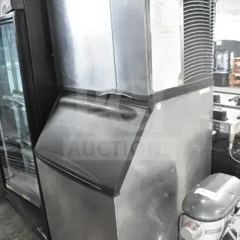 Manitowoc SY0874C commercial ice machine head on ice bin, stainless steel, used, visible manufacturer's label and serial info.
