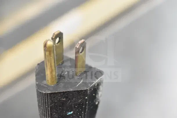 Close-up image of a power plug for a Manitowoc SY0874C commercial ice machine, showing three metal prongs.