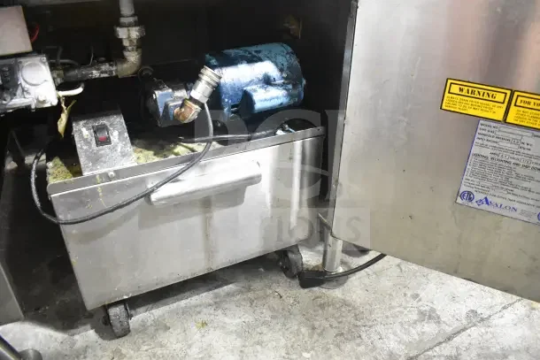 Commercial floor-style donut fryer with visible wear, stainless steel body, attached motor, and warning labels.