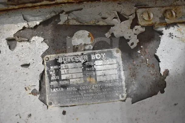 Butcher Boy B14 meat saw label, showing model, 1.5 HP, 220V, 1 phase. Worn with peeling paint and rust.