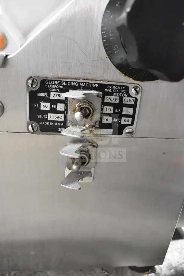 Globe 775L Commercial Meat Slicer with automatic blade sharpener. Operating on 115 volts, 1 phase. Features visible wear.