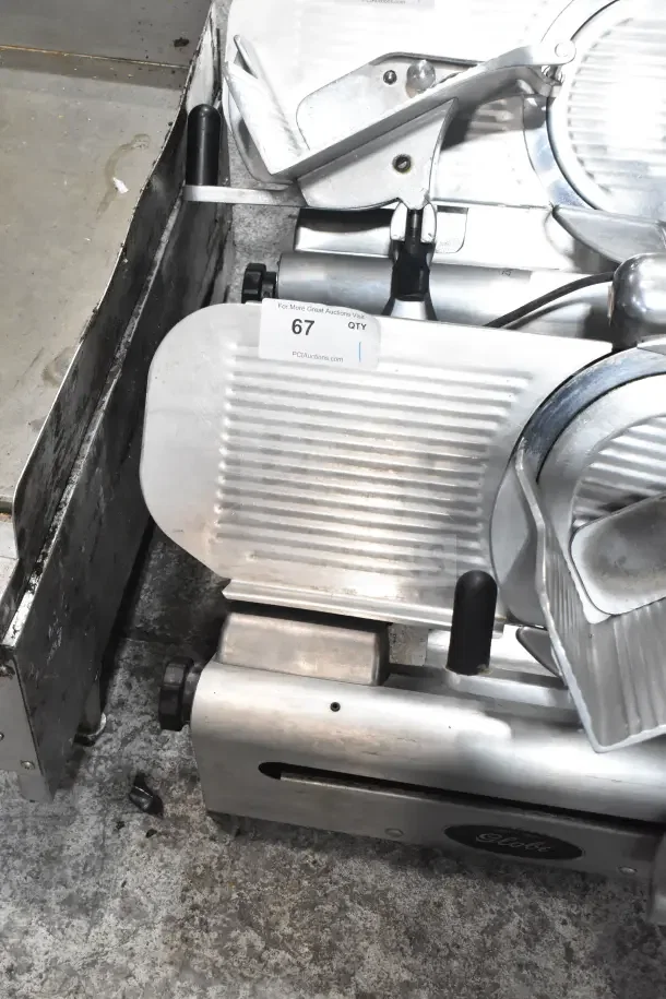Globe 500L commercial meat slicer with blade sharpener, 120V, 1 Phase, displayed on countertop. Auction tag visible.