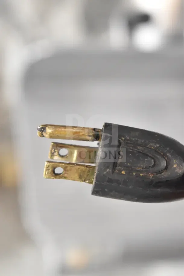 Close-up of the plug from the Globe 500 Commercial Countertop Meat Slicer, showing electrical prongs and slight wear.