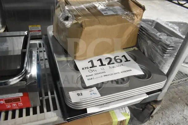 Nine scratch and dent items including a Chicago Metallic 15-cup jumbo muffin pan, wide rim pizza pan, and tapered edge blue carbon steel sheet pan. Tags show item numbers and auction details.