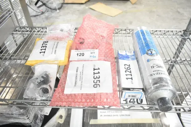Six brand new scratch-and-dent items on a shelf, including Scotsman auger bearing, Pitco computer, Hatco valve, Hoshizaki filter, True temperature control kit, Henny Penny control. Various packaging with visible auction labels.