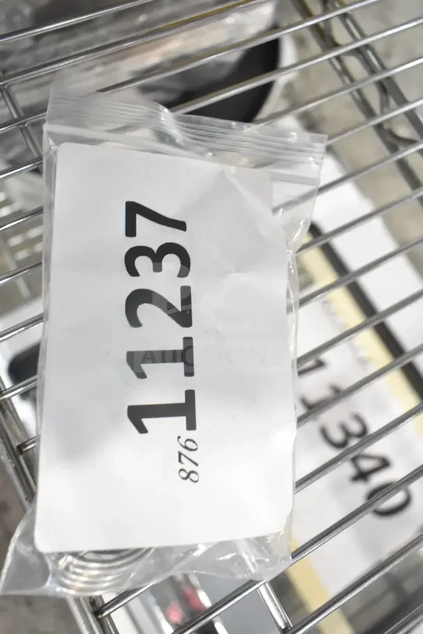 Bag with label "11237" containing various brand new scratch and dent items on wire shelf; includes auger bearing, computer, valve, filter, temperature control kit, and control unit.