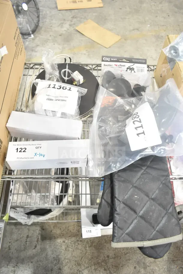 Assorted brand new scratch and dent auction items on a shelf, including a Lavex UV insect zapper bulb, Hobart sharpener assembly, Southbend timer, Outset oven mitt, and suction cup feet for cutters.