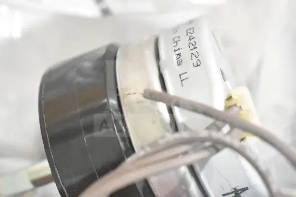 Close-up of a metallic component with visible wiring and "Made in China" marking, part of auction with unused items.